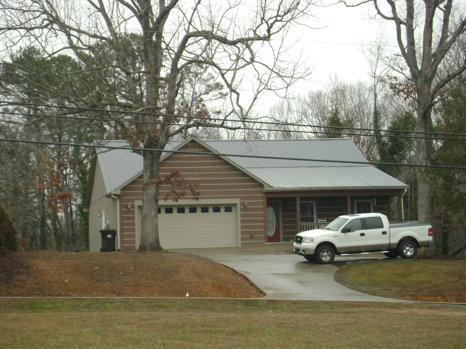 Gray metal roof on a log sided house with an attached two car garage in Tecumseh