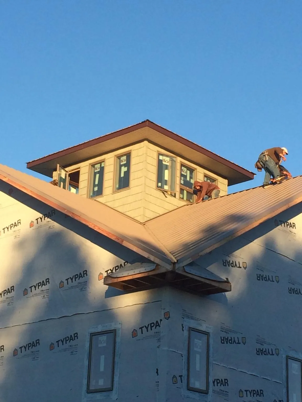 Roofers working around a rooftop cupola on a new metal roof at sunset — Roof Waterproofing in Tecumseh by Roofing Brothers